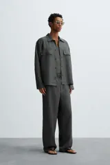 Sobrecamisa de corte relajado color gris oscuro, confeccionada en tejido de cáñamo. Cuenta con cuello de solapa, manga larga con puños abotonados, bolsillos frontales de plastrón con solapa y cierre frontal de botones.