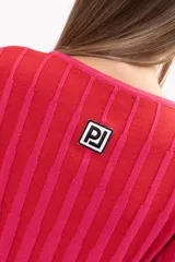 Buzo de punto acanalado con diseño de rayas verticales en tonos fucsia y rojo, de corte ajustado, cuello redondo y mangas largas ligeramente acampanadas.