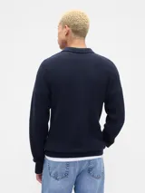 Buzo de punto acanalado color azul marino, con cuello polo y cierre frontal de dos botones. Presenta puños y ruedo elásticos.