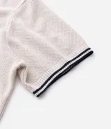 Polo de manga corta con textura en relieve, cuello tipo polo con abertura frontal sin botones y detalles de líneas contrastantes en cuello y puños.