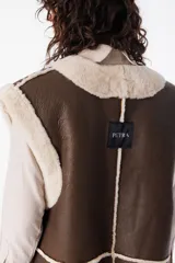 Chaleco reversible de cuero napalan color marrón con interior de corderito color crema. Tiene silueta holgada, terminaciones a la vista y bolsillos laterales.