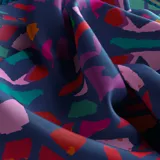 Pañuelo cuadrado de seda color azul con estampado caleidoscópico multicolor y borde azul marino con diseño de cuerda.