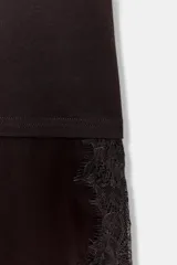 Camiseta de algodón de corte regular, color marrón oscuro o negro, con cuello redondo y manga corta. Presenta un bajo asimétrico con aplicación de encaje negro a tono.