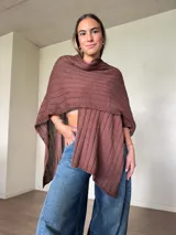 Ruana tejida de algodón con hilo lurex en punto jersey, color azul, con diseño amplio y detalle de etiqueta de cuerina en la parte posterior.