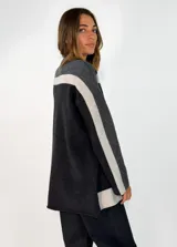Sweater de punto con diseño color block en tonos gris oscuro, negro y gris claro. Presenta cuello alto, mangas largas y un corte holgado.