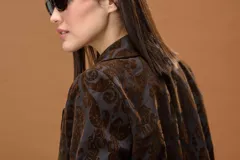 Blazer de corte estructurado confeccionado en tejido jacquard con estampado ornamental en tonos marrones. Presenta solapas clásicas, cierre frontal y diseño de manga larga.