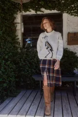 Sweater de lana color crudo con cuello redondo tejido y estampa frontal de un tero. Presenta un diseño de corte holgado con puños y ruedo acanalados.