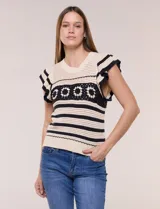 Buzo tejido en punto calado estilo crochet color beige con rayas horizontales negras y una franja central con motivos florales. Presenta cuello redondo, mangas cortas con volados y terminaciones en rib.