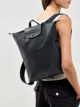 Mochila Longchamp modelo Le Pliage, color negro, confeccionada en nylon con detalles de cuero en la solapa superior. Cuenta con cierre de cremallera, correas ajustables y asa superior.