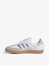 Zapatillas Adidas Samba OG blancas con detalles en plateado y suela de goma color caramelo.