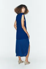 Vestido midi de color azul eléctrico con cuello subido y diseño sin mangas. Presenta un cuerpo liso y una falda con caída fluida y detalle de tul en el bajo.