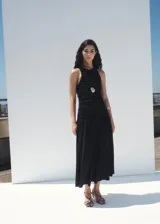 Vestido midi negro sin mangas, con cuello redondo, fruncidos en el cuerpo y falda de corte evasé.