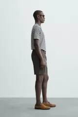 Bermuda de hombre color beige claro, corte regular fit, con pliegues frontales, bolsillos delanteros y bolsillos traseros de doble vivo con botón.