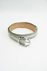Cinturón de tejido trenzado en tonos verdes con acabado brillante, hebilla ovalada de metal plateado y reverso en color natural.