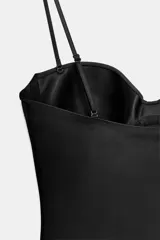 Vestido corto negro con escote corazón, aros en el busto y tirantes finos ajustables. Presenta costuras verticales decorativas a lo largo del frente.