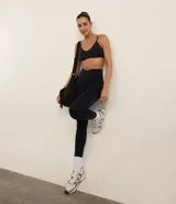 Top deportivo negro, tipo bralette, con escote en V y tirantes finos ajustables.