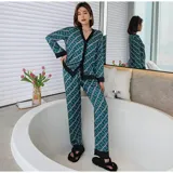 Conjunto de pijama de dos piezas compuesto por una camisa de manga larga con cuello mao y cierre frontal de botones, y un pantalón largo. Presenta un diseño estampado de corazones sobre fondo negro con detalles en color blanco.