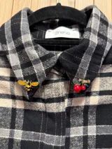 Camisa de franela escocesa en tonos bordó, negro y crudo, con cuello con pins sorpresa y cierre frontal oculto con botones.