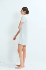 Camisón corto de color gris claro, con escote en V y mangas cortas, decorado con delicados detalles de encaje en el cuello y los bordes de las mangas.