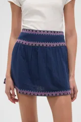 Minifalda azul marino con elástico fruncido en la cintura y el ruedo, ambos adornados con una banda de bordado étnico en tonos rosados y morados.