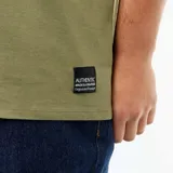 Remera de manga corta con cuello en V, confeccionada en tejido de punto color verde oliva. Presenta un corte clásico y una pequeña etiqueta decorativa en el ruedo inferior.