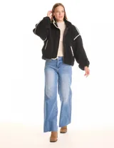 Campera negra de símil corderito, marca Elan. Tiene cuello alto, cierre frontal con solapa y botones, bolsillos inclinados en la parte delantera y ruedo y puños elastizados. Forro interno a tono.