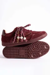 Zapatillas urbanas de gamuza color marrón, con diseño de cordones decorados con cuentas de piedra y detalles de líneas brillantes en los laterales. Presentan suela de goma texturizada al tono.