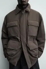 Chaquetón de corte regular fit confeccionado en tejido técnico repelente al agua, con ligero acolchado interior. Presenta cuello solapa, cierre frontal con cremallera oculta por solapa con botones a presión, mangas largas con puños ajustables y múltiples bolsillos de plastrón con solapa en el delantero.
