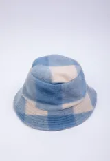 Gorro tipo bucket de textura peluda, con estampado a cuadros en tonos azules y beige.