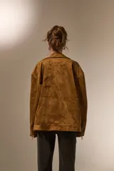 Chaqueta tipo biker de gamuza sintética negra, con cuello solapa, cierre frontal asimétrico y bolsillos con cierre.