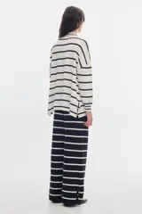 Sweater de punto a rayas horizontales blancas y negras, con cuello alto, fit oversized, tajos laterales y bordado 'PASTICHE CLUB' en color lila en el pecho.