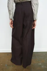 Pantalón de tiro medio con diseño de pierna ancha y estampado de cuadros pequeños. Presenta pinzas frontales, trabillas en la cintura, bolsillos laterales ocultos y cierre frontal con cremallera, botón y ganchos metálicos.