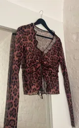 Blusa de microtul con estampado animal print en tonos marrones y negros, con escote en V y mangas largas.