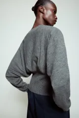 Jersey de punto color gris, con cuello redondo, manga larga y detalle de cintura ajustada con tejido tipo nido de abeja.