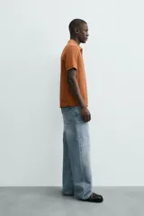 Polo de manga corta color blanco roto, con cuello solapa y cierre frontal de cremallera. Presenta un tejido de piqué estructurado y corte regular fit.