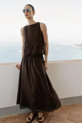 Falda midi marrón oscuro, con diseño fluido y voluminoso, tiro alto y detalles de bordados a tono en el ruedo.