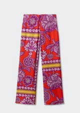 Pantalon palazzo de tiro alto con estampado floral y geométrico en tonos rojos, violetas y amarillos. Confeccionado en tejido fluido con cierre lateral de cremallera.