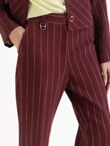 Pantalon de sastreria color bordeaux con diseño de rayas finas verticales blancas, de tiro alto y pierna recta.