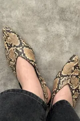 Zapatos planos de cuero con estampado de serpiente, punta fina y diseño destalonado.