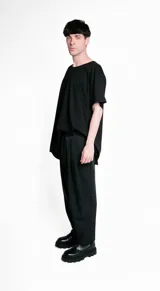 Pantalón de vestir negro, de corte recto, con bolsillos laterales y traseros. Se ajusta a la cintura con cinturón de cuero marrón.