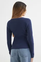 Sweater color beige de tejido de punto acanalado, con cuello redondo y mangas largas.