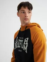 Canguro negro y ocre con capucha y cuello en rib, manga raglán, bolsillos laterales y estampa combinada (estampa y bordado).