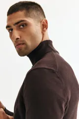 Buzo de punto fino con cuello alto acanalado, manga larga y terminaciones en rib en puños y bajo. Presenta un diseño de corte estándar y silueta clásica.