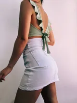 Crop top negro con textura brillante, breteles anchos con volados y espalda descubierta que se ata con lazos.