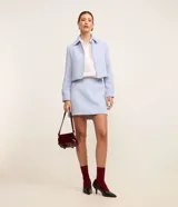 Short pollera de tiro medio confeccionado en tejido tweed texturizado color celeste. Presenta un diseño corto con cintura fija y cierre lateral con cremallera.