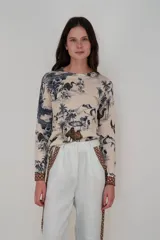 Sweater de cashmere color beige con estampado de paisaje con camellos, palmeras y aves en tonos azul y marrón.