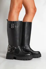 Borcegos negros de ecocuero con caña alta y base con plataforma. Presentan correas con hebillas plateadas en la parte superior y alrededor del tobillo.