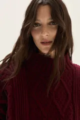 Polera de tejido de punto con diseño de ochos y detalles de tientos en contratono en las mangas. Presenta cuello alto y corte cropped.