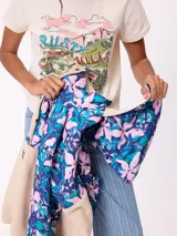 Canguro de estilo deportivo con diseño combinado, parte superior con estampado floral en tonos azules y rosados, y parte inferior de tejido tipo sherpa en color beige. Cuenta con cuello alto, cierre frontal parcial y bolsillo tipo canguro frontal con logo de la marca.