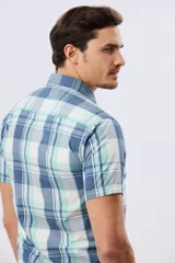 Camisa de manga corta con estampado de cuadros en tonos celestes, azules, blancos y verdes, con cierre frontal de botones y bolsillo ojal en el pecho.